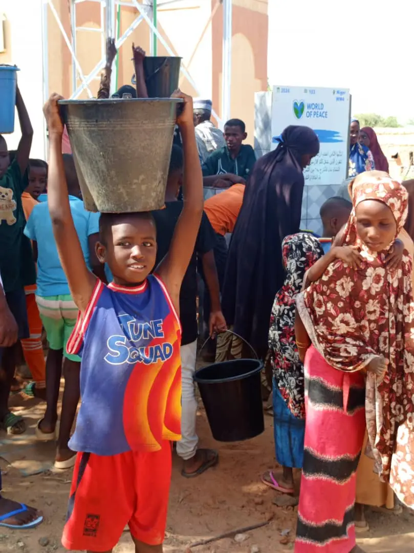 Boy with a water bucket at a World of Peace well