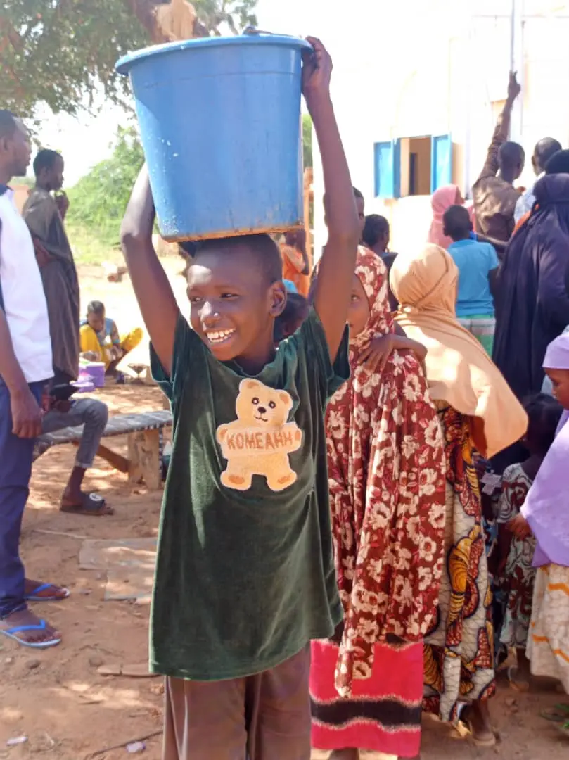 Child with a water bucket at a World of Peace well