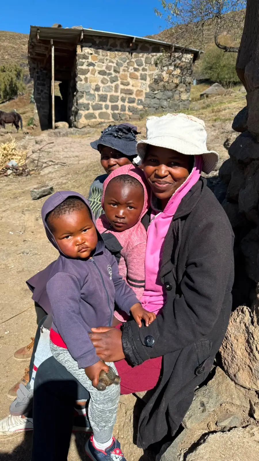 Mutter mit Kindern vor einem Steinhaus in Lesotho